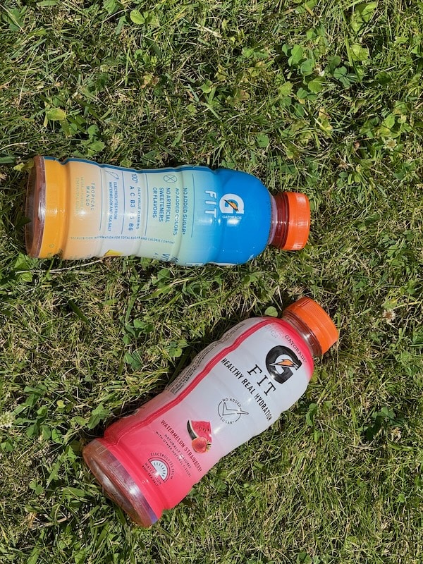 two bottles of Gatorade fit lying in the grass