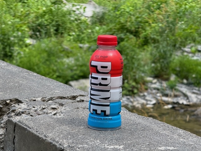 one bottle of prime hydration on a barrier in the woods