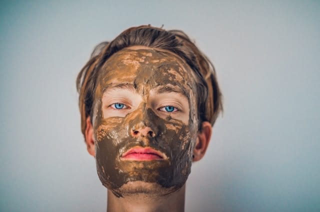 a young man wearing a brown facial mask